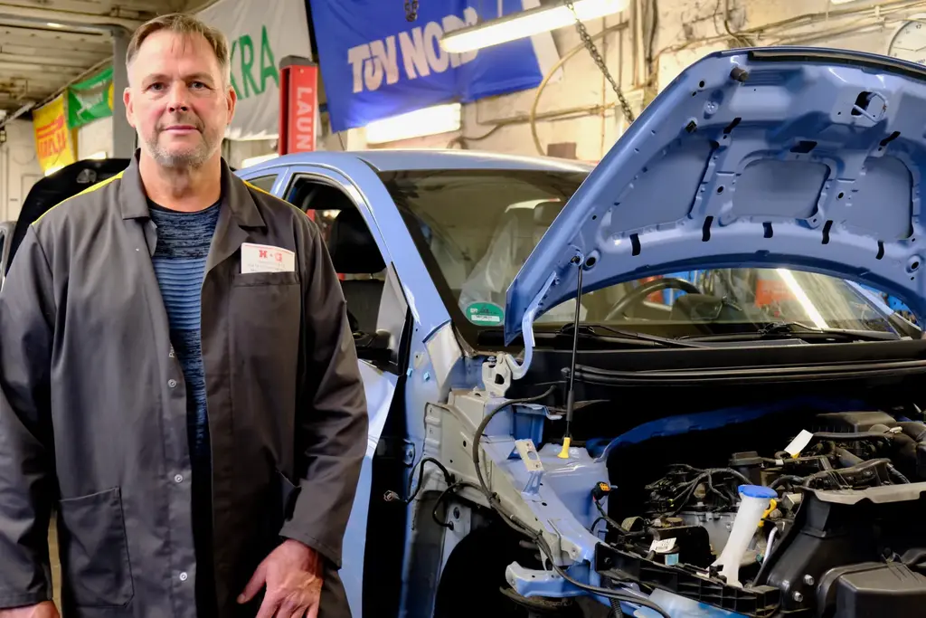 Kfz-Meister Gerhard Gaber in der Werkstatt neben einem Auto mit geöffneter Motorhaube