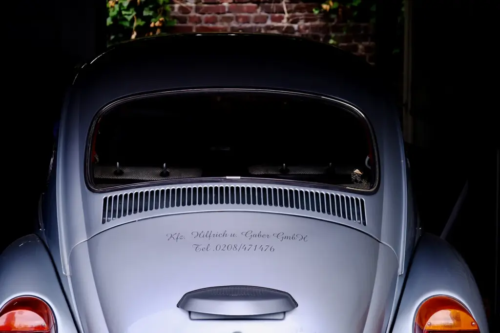Heck eines silbernen VW Käfer mit dem Schriftzug Kfz Hilfrich u. Gaber GmbH