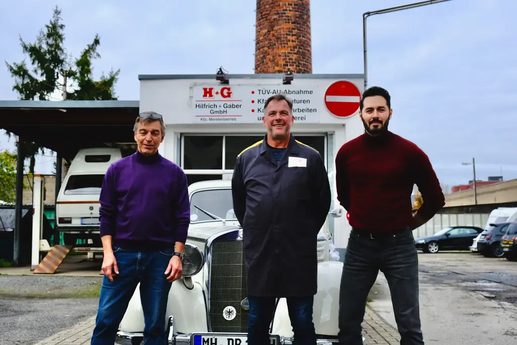 Gerhard Gaber, Andre Kasten und Frank vor dem Firmenschild von Hilfrich + Gaber mit einem Mercedes-Oldtimer